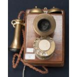 A brass and mahogany wall mount telephone with modern wall socket