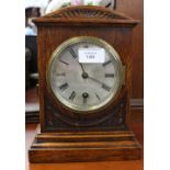 An early 20th Century oak eight day mantle clock, with a silvered dial and black Roman numerals,