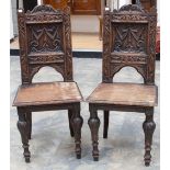 A pair of Victorian Renaissance Revival oak hall chairs, with carved backs,