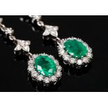 A pair of pendant cluster earrings each set with oval emerald surrounded by brilliant cut diamonds