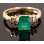 A single stone ring set with a step cut emerald with baguette cut diamonds to shoulders,