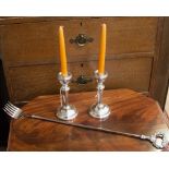 A pair of silver plated weighted candlesticks, together with a plated toasting fork,