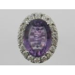 An amethyst and diamond set white metal dress ring, the oval faceted amethyst set diamond