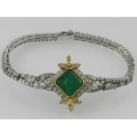 An 18 carat white gold, emerald, and diamond set line bracelet, centred with an asher cut emerald