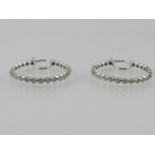 A pair of 18 carat white gold and diamond hoop earrings, the stones of approx. 0.52 carats combined.