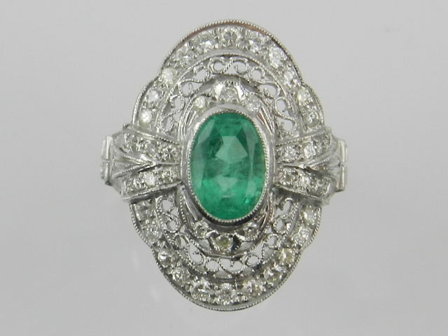 A Belle Epoque style of emerald and diamond mounted dress ring, oval cluster form, the shank stamped