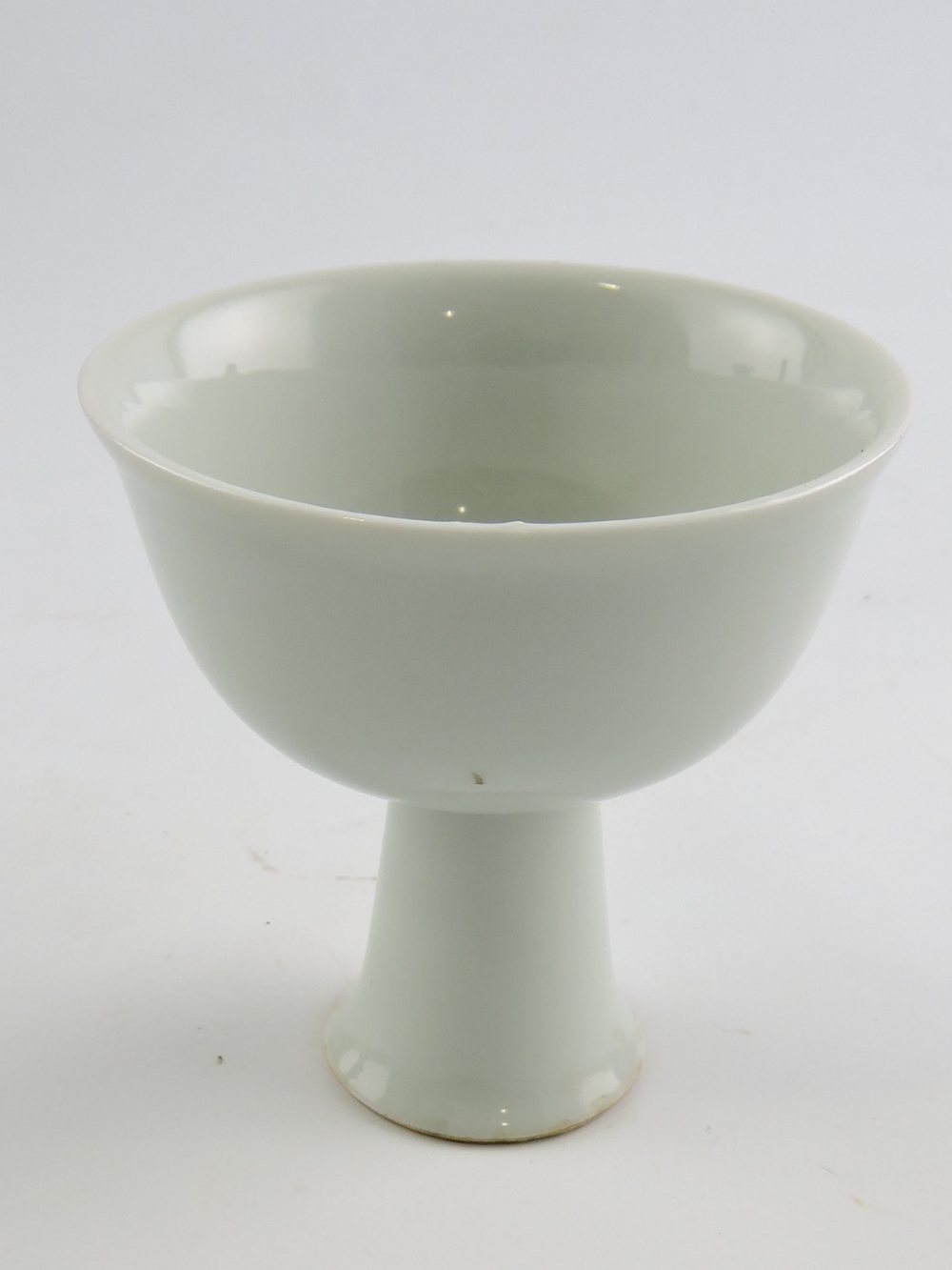 A white glazed bowl, raised on a tall ta