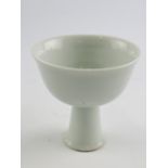 A white glazed bowl, raised on a tall ta