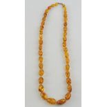 An amber bead necklace, the graduated ov