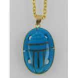 A yellow metal mounted double sided turquoise pendant in the form of a scarab, suspended on a yellow