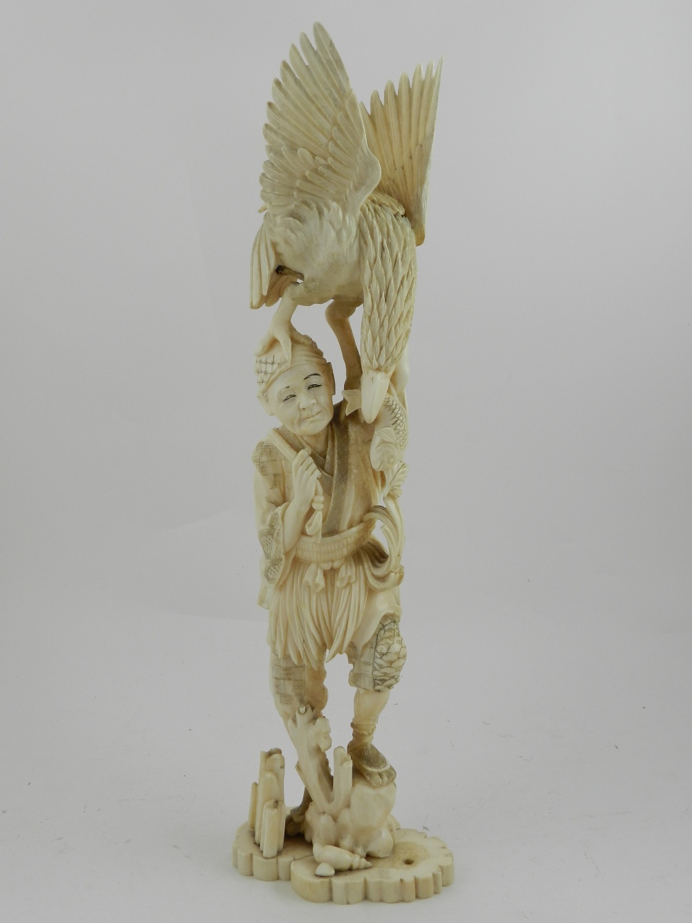 A Japanese Meiji period carved ivory okimono, a figural study of a falconer with bird of prey