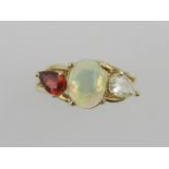 A yellow metal, diamond, opal, and ruby set ring, the central oval cabouchon opal flanked by a