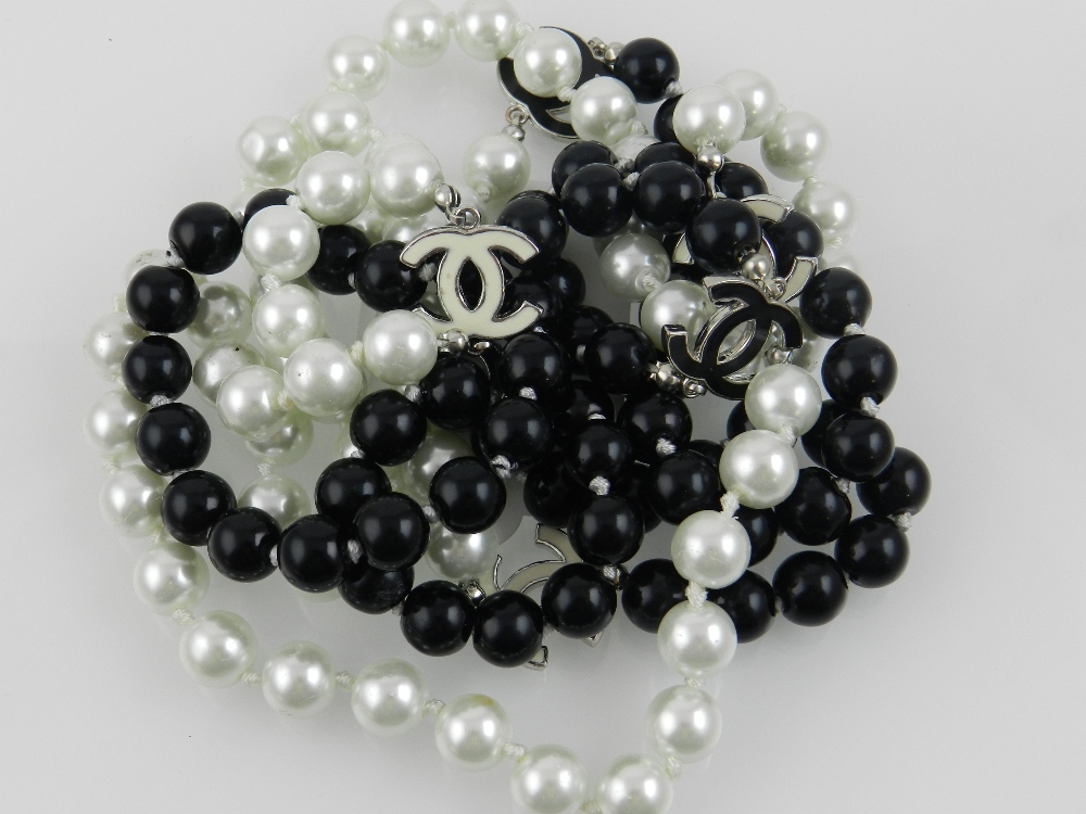 A Chanel style black and white pearl necklace, having enamelled fifi embellishment.