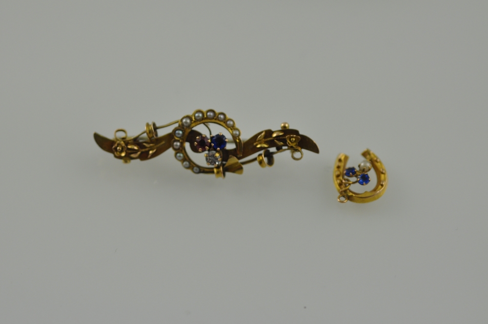 A yellow metal bar brooch, set with blue, red and white stones within a hoop of pearls, marked 9ct;