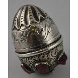 A white metal egg-shaped trinket box, set with uncut gemstones, possibly ruby, and inscribed