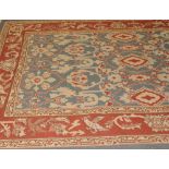 A Persian style wool rug, with a foliate pattern on a blue ground within a iron red border, 260 x