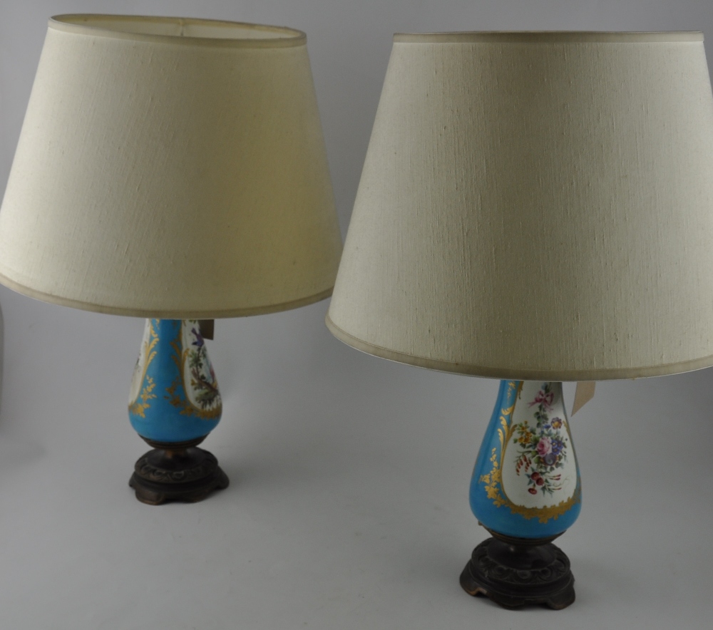 A pair of Serves style porcelain table lamps, decorated with gilt framed vignettes of birds and