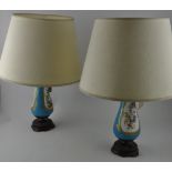 A pair of Serves style porcelain table lamps, decorated with gilt framed vignettes of birds and