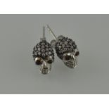 A pair of encrusted ear studs, in the form of skulls with red eyes, stamped 925.