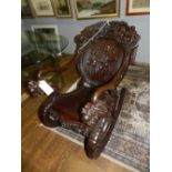 An unusual Chinese carved hardwood rocking chair, having a relief carved dragon cresting rail,