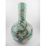 A Chinese mottled green porcelain baluster bottle vase, decorated with songbirds amongst a prunus