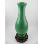 A Chinese porcelain green crackle glaze baluster vase, raised on a carved hardwood base. H.33cm