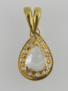 A yellow metal and diamond set pendant, centered with a pear-cut diamond, on an openwork mount.