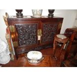 An early 20th century Chinese carved padauk wood side cabinet, fitted with a pair of fielded