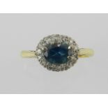 A yellow metal diamond and blue stone (possibly sapphire) set cluster ring.