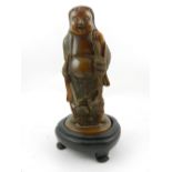A Chinese carved soapstone, modelled as a Buddha, set in a wooden stand. H.24cm