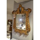 An 18th century Venetian style carved giltwood looking glass, having a relief moulded foliate frame,