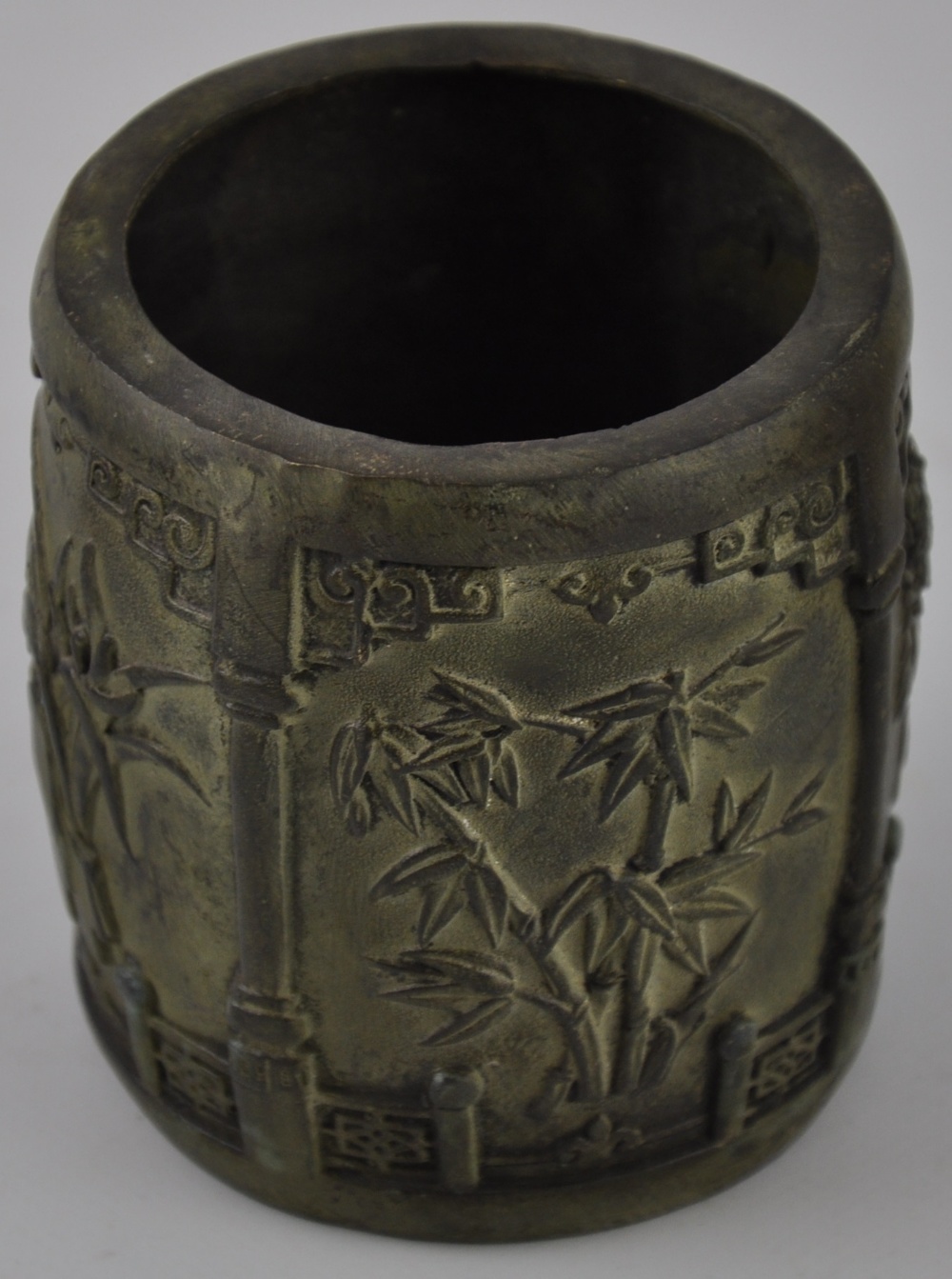 A Chinese style circular aged metal brush pot cast with panels of peoney and bamboo, H. 10cm.