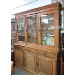 A late Victorian oak library bookcase enclosed by three glazed doors over three frieze drawers and