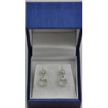 An 18ct white gold screw back Art Deco style round brilliant cut and princess cut drop earrings.