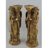 A pair of gilt candlestands in the form of angels, the winged figures holding an octagonal support,