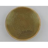 A celadon glazed dish, the interior decorated with a dragon chasing a flaming pearl, D. 19.5cm.