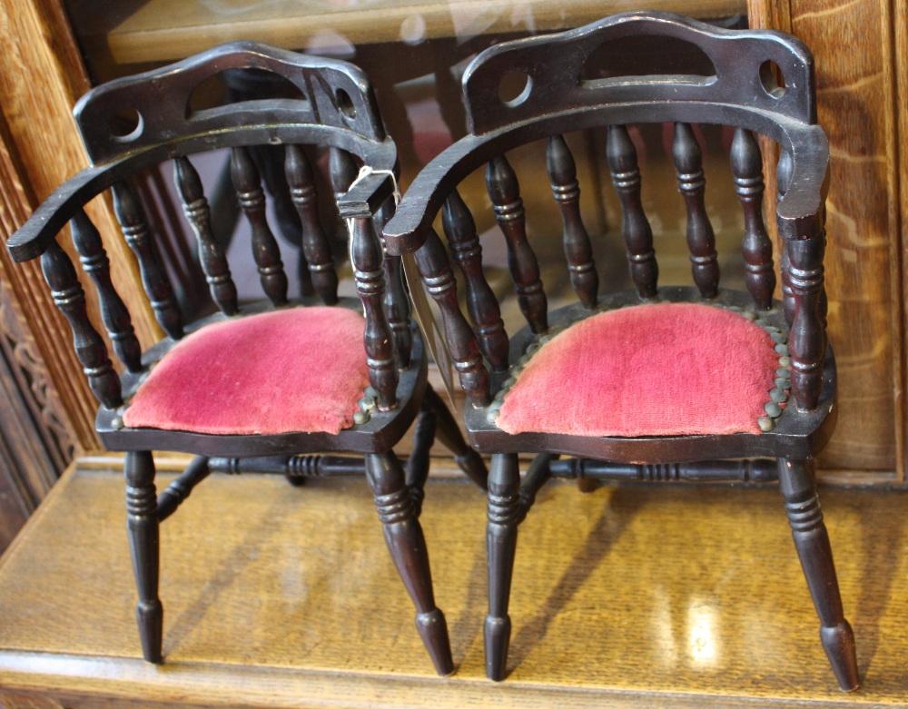 A pair of miniature Windsor smokers bow chairs with buttoned and padded seats above turned uprights