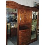 An Edwardian marquetry inlaid mahogany wardrobe with central cupboard over three bowed drawers
