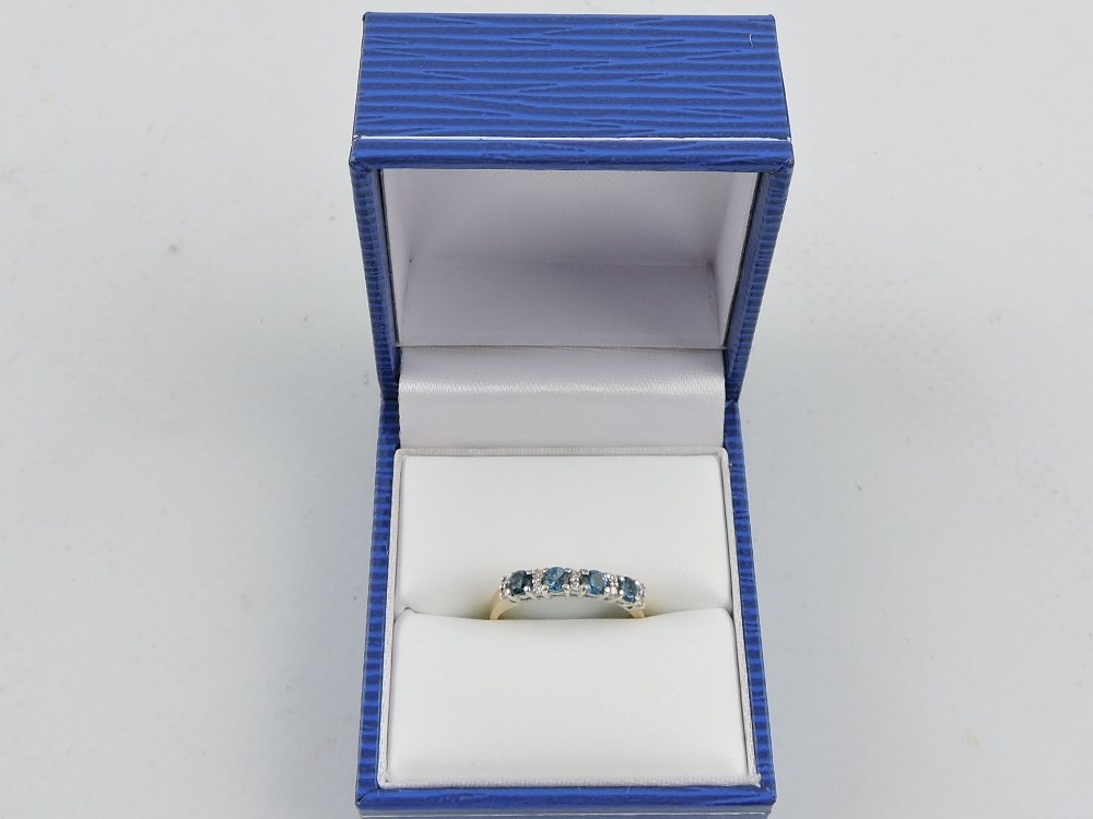 A 9ct gold dress ring, four blue topaz stones divided by pairs of diamonds, 2g.