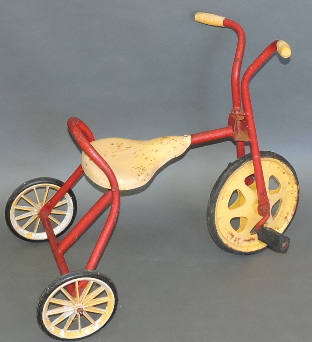 A late 20th century tin-plate and tubular steel child's tricycle, painted yellow and red,