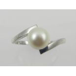 A white metal and pearl set crossover style ring, the shank stamped 14K.