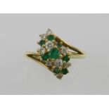 An 18 carat yellow gold, diamond, and emerald cluster ring.