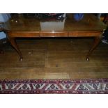 A Queen Anne style figured walnut extending dining table, having a moulded top,