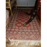 An Afghan red ground rug, decorated with geometric pattern, multi-bordered and fringed.