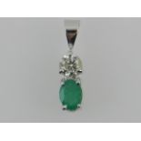 A white metal, diamond, and emerald set pendant.