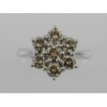 An 18 carat white gold and diamond flower cluster ring, set with seven matching champagne