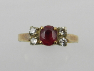 A yellow metal, diamond, and red stone (possibly ruby) ring.