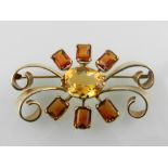 A yellow metal and citrine set bar brooch with of symmetrical scrolling design,