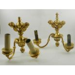 A pair of 19th century ormolu wall lights, having two twin-headed cherub finials.