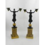 A pair of bronze candlesticks, in the form of a woman holding her arms,